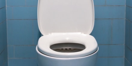 Modern toilet bowl near color wall